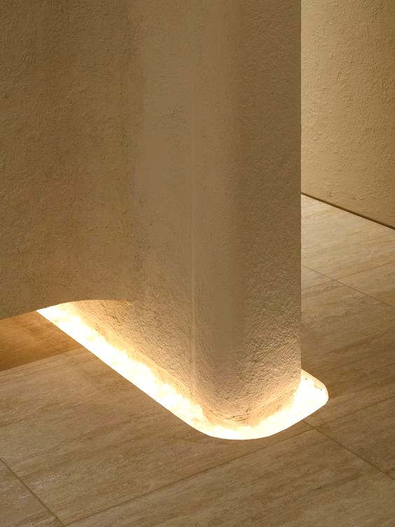 A soft warm alabaster wall, light glowing at its base — the cabin's interior register